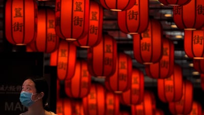 A woman wearing a face mask looks as she walks through red lanterns on display at a subway station in Beijing, Sunday, June 26, 2022. (AP Photo / Andy Wong)
