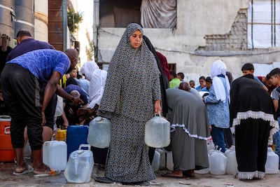 Displaced Palestinians fill water containers from a cistern at a shelter camp in Khan Younis. AFP