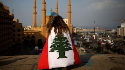 A Lebanese anti-government protester, draped in a national flag, sits on the rooftop of 'The Egg' buidling overlooking the Mohammed Al Amin mosque and Martyrs square in Beirut. AFP