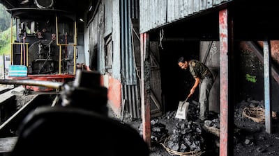 A worker breaks coal for a steam engine belonging to Darjeeling Himalayan Railway at a station in Darjeeling.