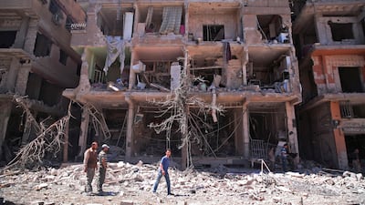 Syrians walk past a damaged building in Ain Tarma, in the eastern Ghouta area, a rebel stronghold east of the capital Damascus on June 21, 2017. Msallam Abdalbaset / AFP