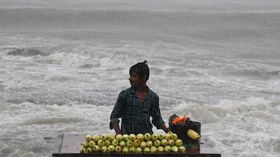 A corn seller waits for customers during rain showers near the sea front in Mumbai on July 8. AFP