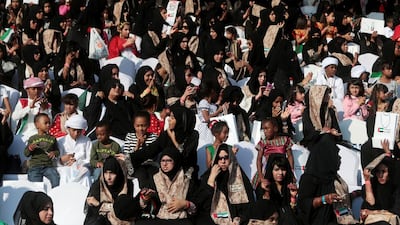 Women wait for the start of the military parade.