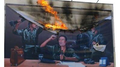 Libyans burn a poster in Tripoli Saturday showing Muammar Qaddafi making his revolution announcement in 1969.