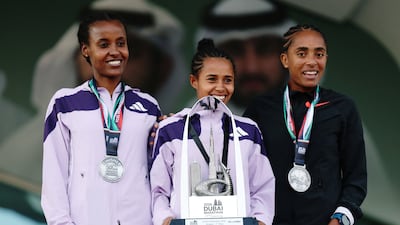 A one-two-three for Ethiopia's elite women runners in the Dubai Marathon 2025. Winner Anchinalu Dessie celebrates on the podium with runner-up Muliye Dekebo and third-placed Fantu Worku