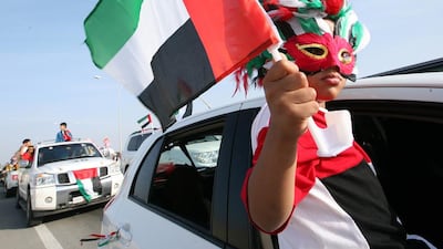 A child waves a UAE flag during the car parade in celebration of the 38th anniversary of Federation in Umm Al Quwain. Paulo Vecina / The National