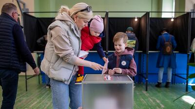 A woman with children casts her ballot in Vilnius, Lithuania. Polls closed at 8pm local time, with results expected after midnight. AP