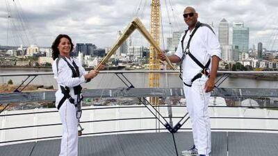 Torchbearers Nadia Comaneci, left, and John Amaechi as they hand over the Olympic Torch on a viewing platform in North Greenwich Arena today.
