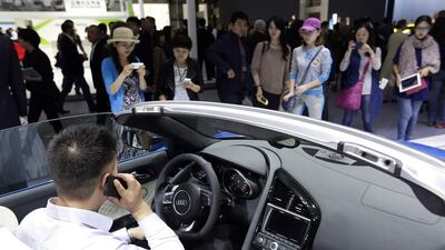 A visitor uses his mobile phone as he sits in an Audi R8 Spyder during Auto China 2014 in Beijing, on April 20. Jason Lee / Reuters