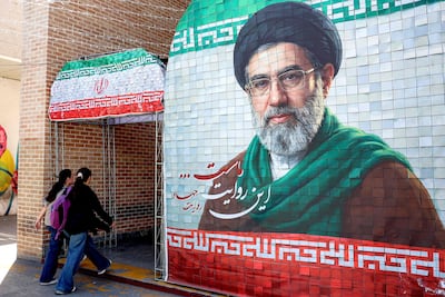Women walk past a banner depicting Iran's supreme leader Ayatollah Mojtaba Khamenei. AFP