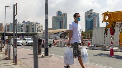 A man carries his shopping while wearing a face mask in Dubai. Chris Whiteoak/The National