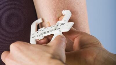 Trainer measuring body fat percentage. Getty Images/Tetra images