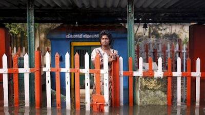 A woman stands at a fenced gate of a partially submerged temple in Chennai, India, December 4, 2015. REUTERS/Anindito Mukherjee