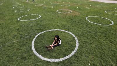 A girl sits in a field where circles were painted to help visitors maintain social distancing at Trinity Bellwoods park in Toronto, Ontario, Canada. Reuters