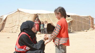 A member of the UAE Red Cresent speaks with a Syrian refugee. Wam