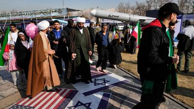 Demonstrators walk over Israeli and US flags at a rally commemorating Iran's 1979 Islamic Revolution, in Tehran in February 2024. AP