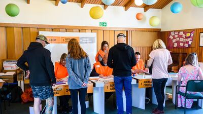 Voters receive their ballot papers from election officials at a polling station during the New Zealand General Election in Auckland. Bloomberg