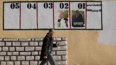 A man walks past empty or defaced electoral posters in Ain Soussera, south of Algiers. AP Photo