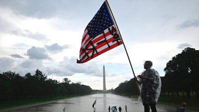 A demonstrator waves an American flag with the words "Not Free" painted on it in front of the Washington Monument. AFP