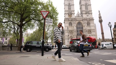 A tourist poses for a photo underneath a polling station sign near Westminster Abbey during local elections in London. Reuters