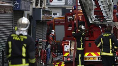 Firefighters work at the scene where a fire in an apartment building in the north of Paris killed eight people early on Wednesday. Kenzo Tribouillard / AFP