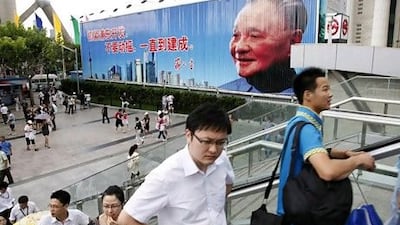 Pedestrians ride an escalator past a poster of Deng Xiaoping, the architect of China's economic reform, in Shanghai in 2010.