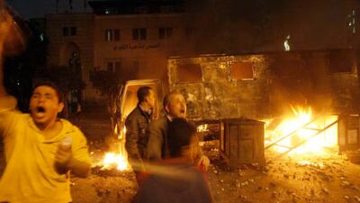 Thousands are defying the Cairo curfew as they continued to try storming two major government buildings - the state television of Foreign Ministry. Above, protesters shout slogans next to a burning riot police vehicle in Cairo.
