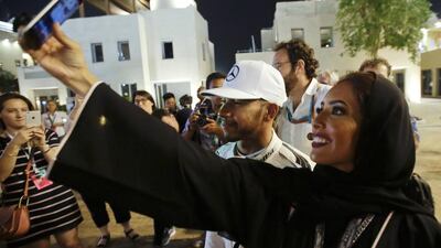 Mercedes driver Lewis Hamilton of Britain, center, is surrounded by fans after the qualifying session at the Yas Marina racetrack in Abu Dhabi, United Arab Emirates, Saturday, Nov. 26, 2016. The Emirates Formula One Grand Prix will take place on Sunday. (AP Photo/Luca Bruno)