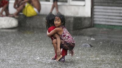 A Filipino girl is carried along a flooded road in suburban Mandaluyong, east of Manila, Philippines, as monsoon downpours intensify. Aaron Favila / AP