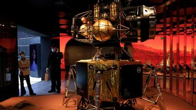 A security guard and worker stand near a depiction of a Chinese lander in a Mars-like environment in Beijing. AP Photo