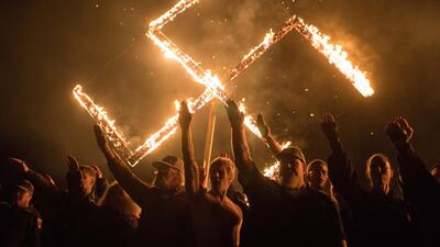 Supporters of the National Socialist Movement, a white nationalist political group, give Nazi salutes while taking part in a swastika burning at an undisclosed location in Georgia, on April 21, 2018. Reuters