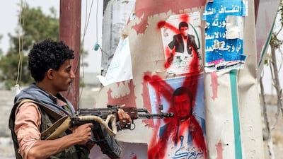 A Yemeni fighter from the Amalqa ("Giants") Brigades loyal to the Saudi-backed government stands pointing a Kalashnikov assault rifle towards a crossed-out plastered poster of the Houthi rebel leader Abdulmalik al-Houthi, on the southern outskirts of the Red Sea port city of Hodeidah near the airport on June 21, 2018. Saleh Al-Obeidi / AFP