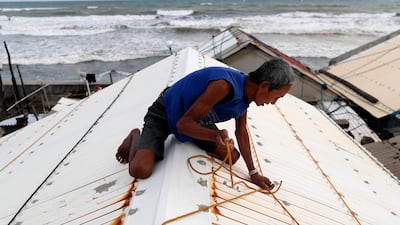A Filipino secures the roof of a house in Aparri, Cagayan province, Philippines. Francis R Malasig / EPA