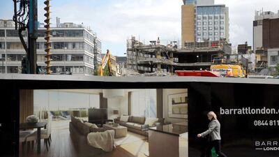 A woman walks past a sign advertising new luxury apartments in London’s East End.tThe Organisation for Economic Co-operation and Development said that Britain should take action over soaring house prices, perhaps by scaling back the government’s mortgage guarantee scheme. Dan Kitwood / Getty Images