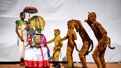 A Kathakali classical dancer, second left, watches artists rehearse the traditional folk dance Pulikkali, known as the Tiger Dance, as they wait backstage before their performance at a cultural festival in Chennai. AFP