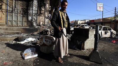 An armed Yemeni stands near destroyed vehicles at a street leading to the residence of Yemen’s ex-president Ali Abdullah Saleh a day after Houthi militants killed him, in Sana’a, Yemen. Yahya Arhab / EPA
