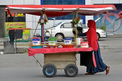 An Afghan woman street vendor pushes her cart along the roadside in Kabul. AFP