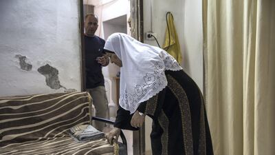 Mohammed Shamasneh watches his mother Fahima as she fixes the blanket covering her sofa after she prayed in her tiny basement home in the East Jerusalem neighbourhood of Sheik Jarrah. Heidi Levine for The National