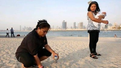 Myrna Rebulanan-Anderson, let, and Rowena Lapus-Torres with her baby boy pick up ring pull tabs.