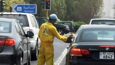A cleaning worker receives money from a motorist in Salmiya, Kuwait during the last 10 days of Ramadan.