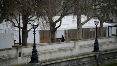 A worker walks past a newly built structure in the grounds of St Thomas' Hospital in central London. For most people, the new coronavirus causes only mild or moderate symptoms, such as fever and cough. For some, especially older adults and people with existing health problems, it can cause more severe illness, including pneumonia. AP Photo
