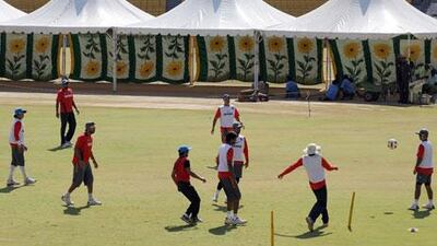 Indian cricketers train beside the tents pitched overhead the playing strip. Prakash Singh / AFP