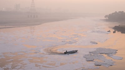 People use boats to break up foam caused by pollution on the Yamuna River in New Delhi, India. Getty Images