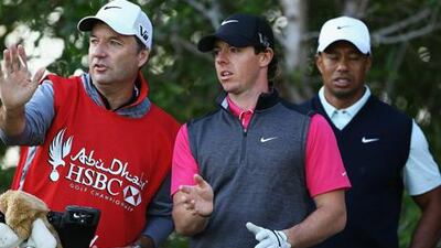 Rory McIlroy consults with caddie JP Fitzgerald while Tiger Woods looks on during day one of the Abu Dhabi HSBC Golf Championship.