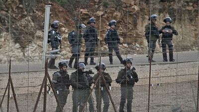 Israeli security forces stand behind a wire fence as Palestinians demonstrate in the northern West Bank city of Tulkarem following the funeral of 19-year-old Badr Nafla in the same city. AFP