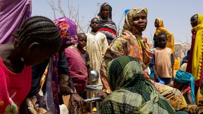 Sudanese refugees gather to fill cans with water from a water point