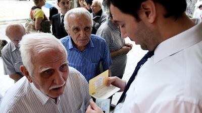 An employee checks the identification and bank booklet of a pensioner before being allowed to enter a bank branch in Thessaloniki. Giannis Papanikos / AP Photo