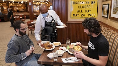 A waiter wearing a face mask serving diners at Junior's Restaurant in New York last week. US restaurant owners are keeping an eye on congressional stimulus talks, with many saying their business’s survival depends on a new federal aid package. AP Photo