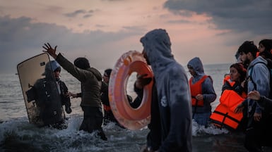A French police officer enters the water to stop people boarding a boat. Getty Images