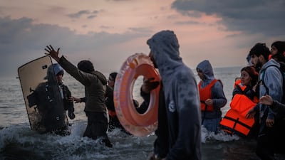 A French police officer enters the water to stop people boarding a boat. Getty Images